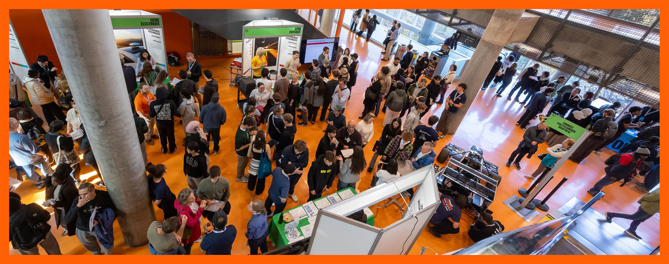 Vue en plongée d’un hall de Polytechnique Montréal animé par de nombreux étudiants et visiteurs.
