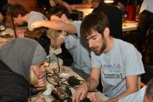 Un bénévole et un participant tentent de remettre un appareil électrique en état de marche.